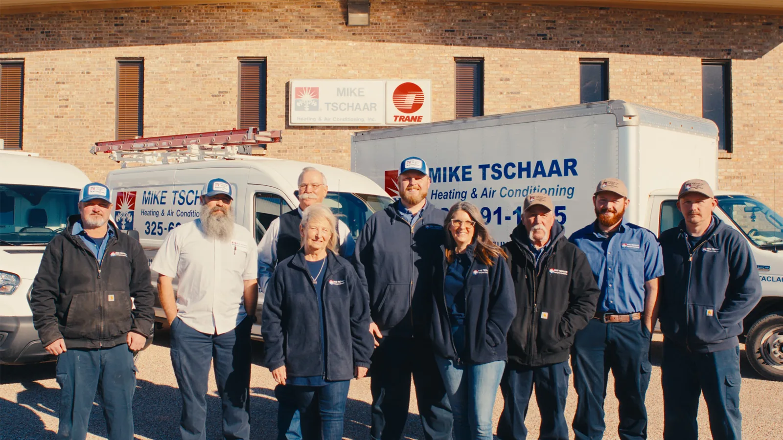 Mike Tschaar staff in front of the company's service trucks