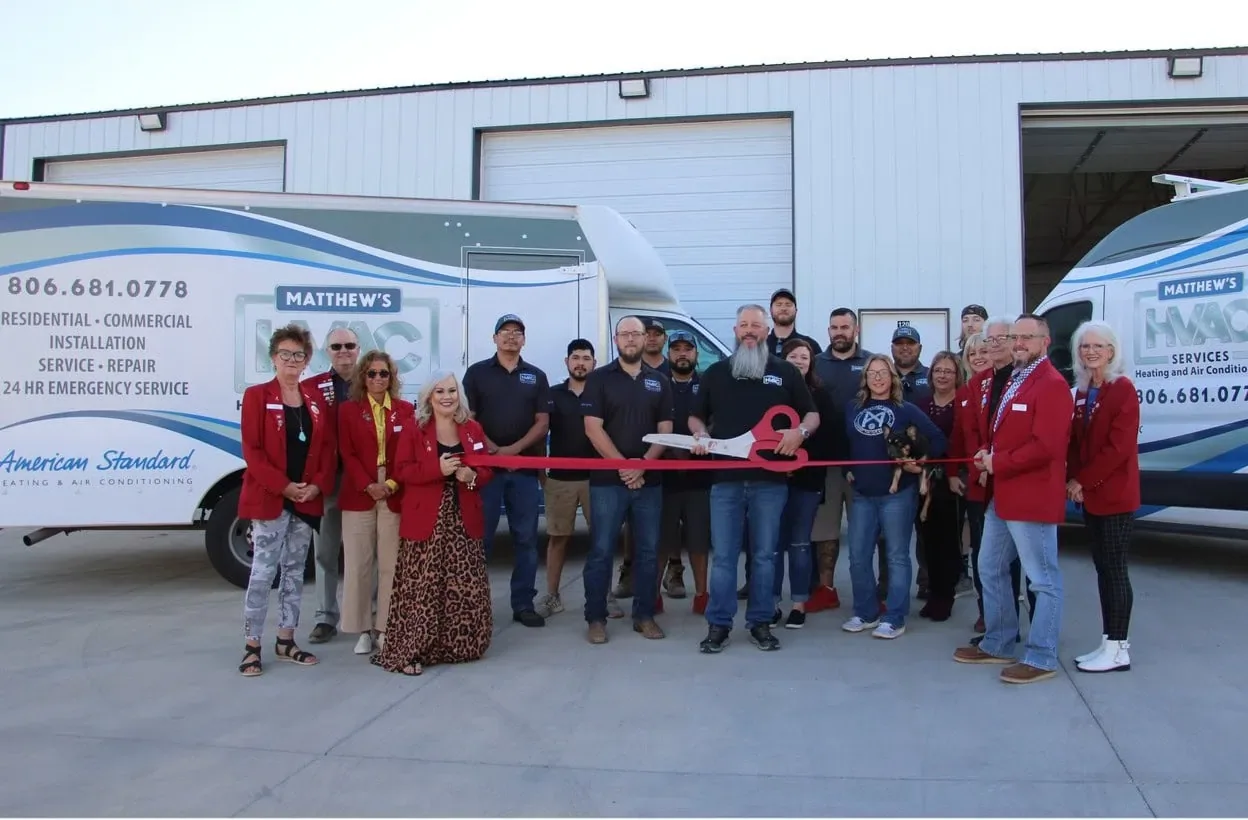 Matthew's HVAC Services staff at a 2024 ribbon cutting in front of the company vans