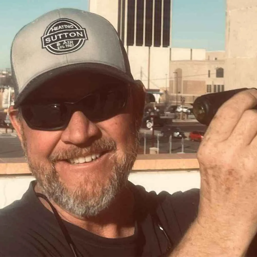 Sutton Heating and Air team member in a company cap on a rooftop job in downtown Amarillo