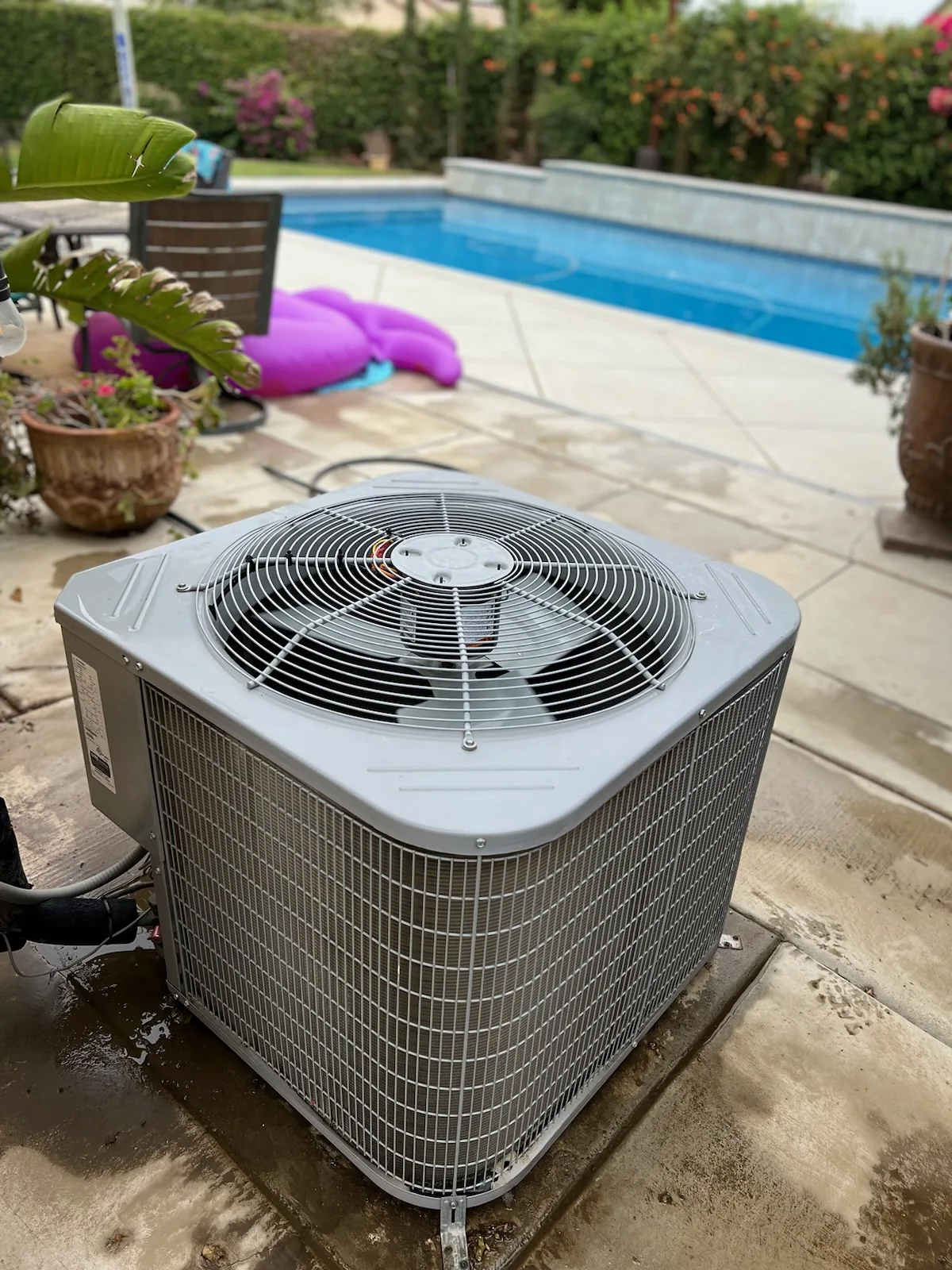 Outdoor air conditioning unit beside a backyard pool, from the On Call website