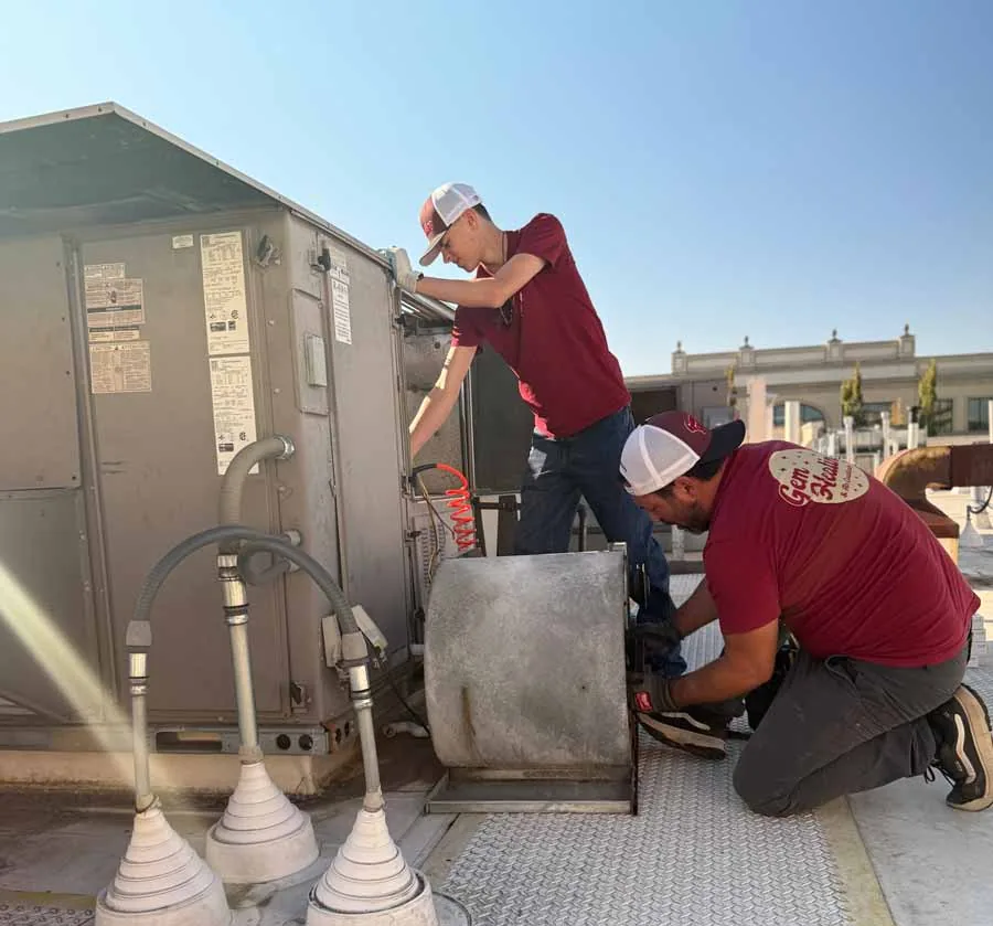 Gem Heating technicians working on a rooftop commercial unit