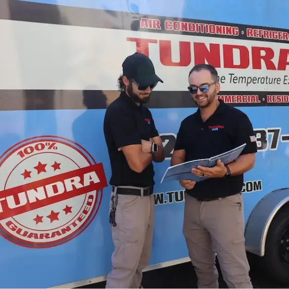 Two Tundra Air staff reviewing paperwork in front of a branded company trailer