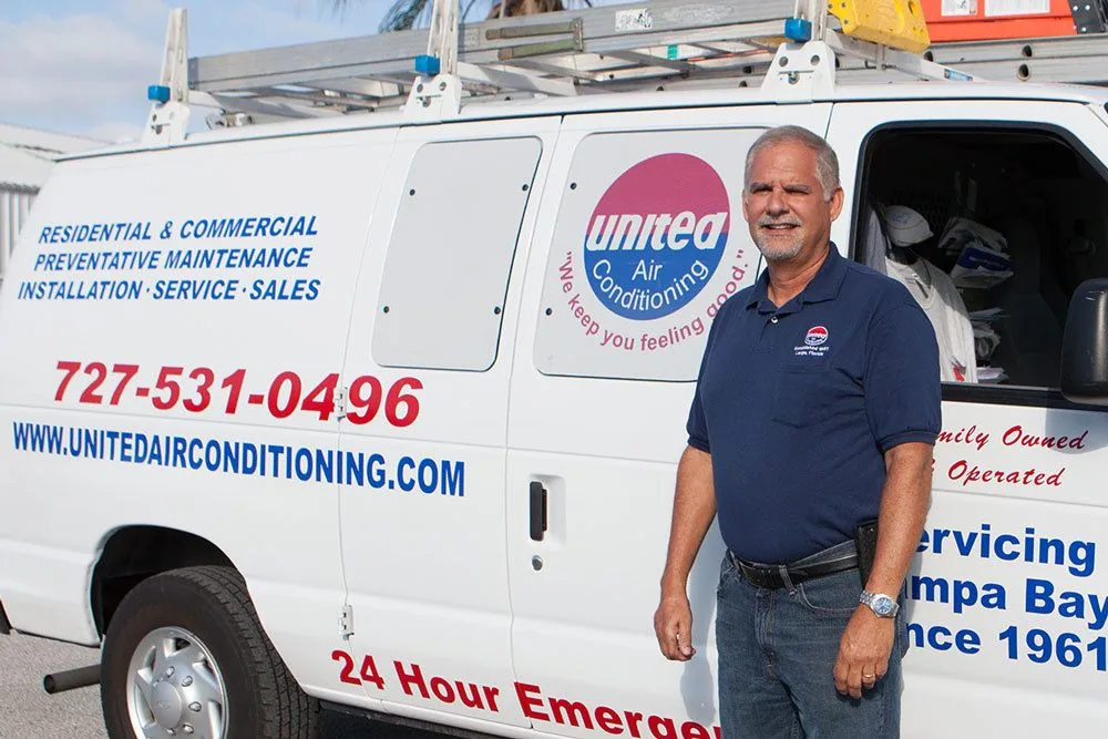 United Air Conditioning team member beside a lettered service van
