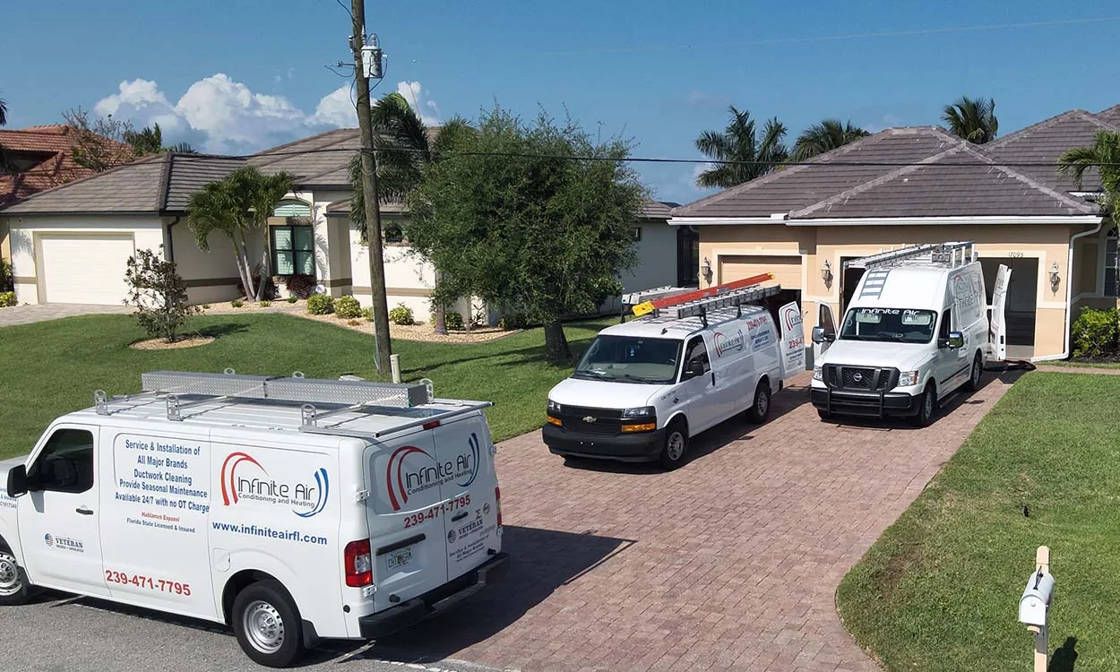Infinite Air Conditioning & Heating service vans parked at a job in a residential street