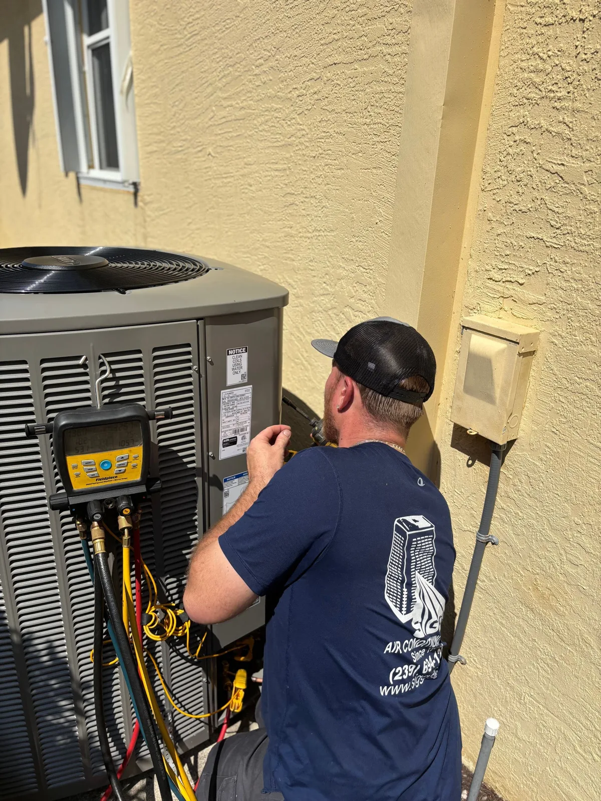 Siggs technician connecting gauges to a new outdoor condenser during an installation