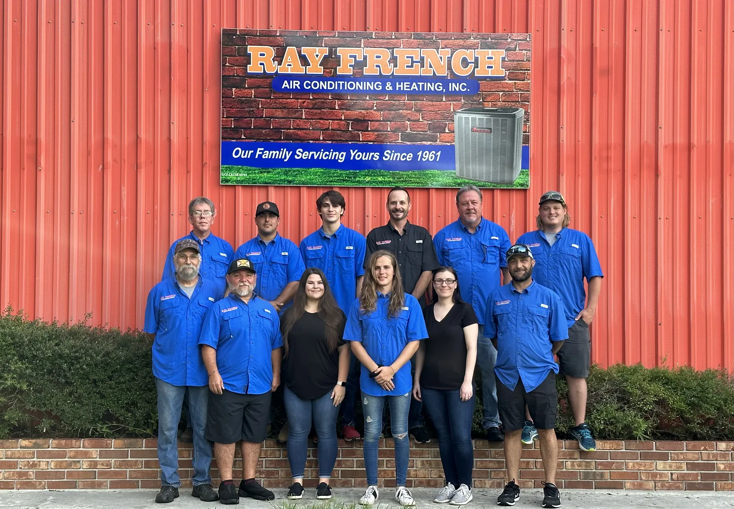 Ray French Air Conditioning & Heating staff in front of the company building sign
