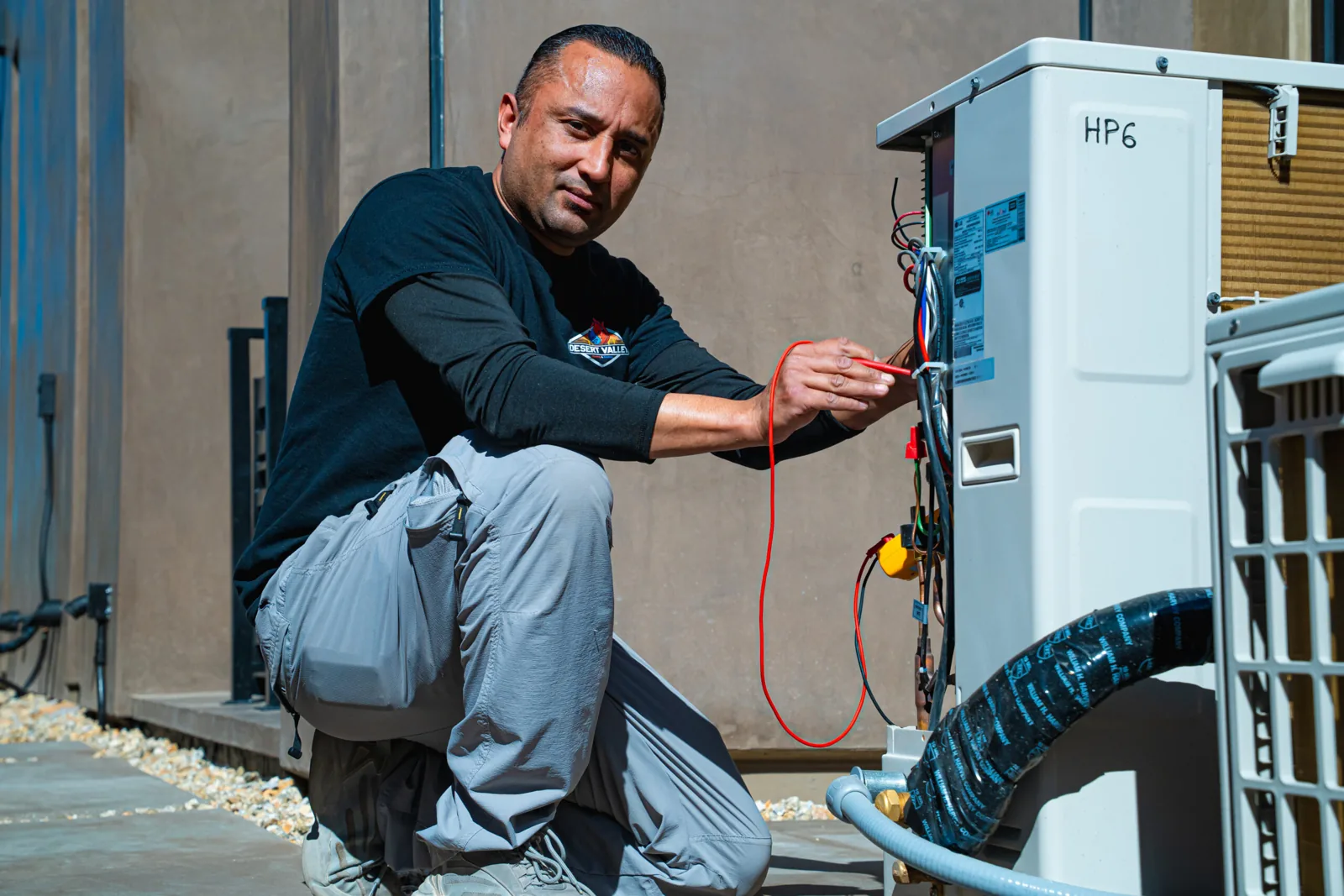 Desert Valley Heating & Cooling technician wiring an outdoor HVAC unit
