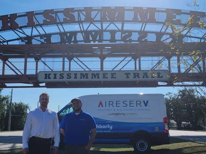 Two Aire Serv team members and a branded van under the Kissimmee Trail sign