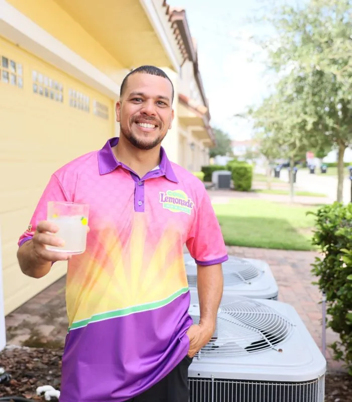 Cool Lemonade Air technician next to outdoor AC units