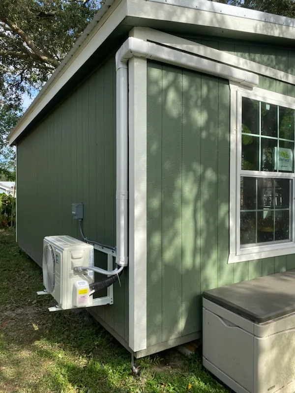 Mini-split outdoor unit installed on the side of a backyard building