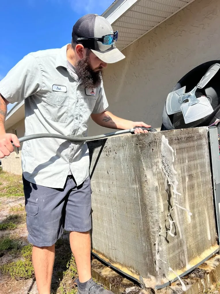 Expedited Home Services technician cleaning an outdoor AC coil