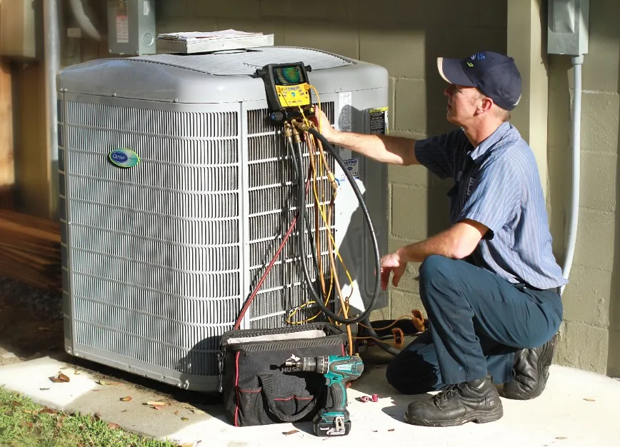 Payne Air technician checking refrigerant pressures at an outdoor condenser