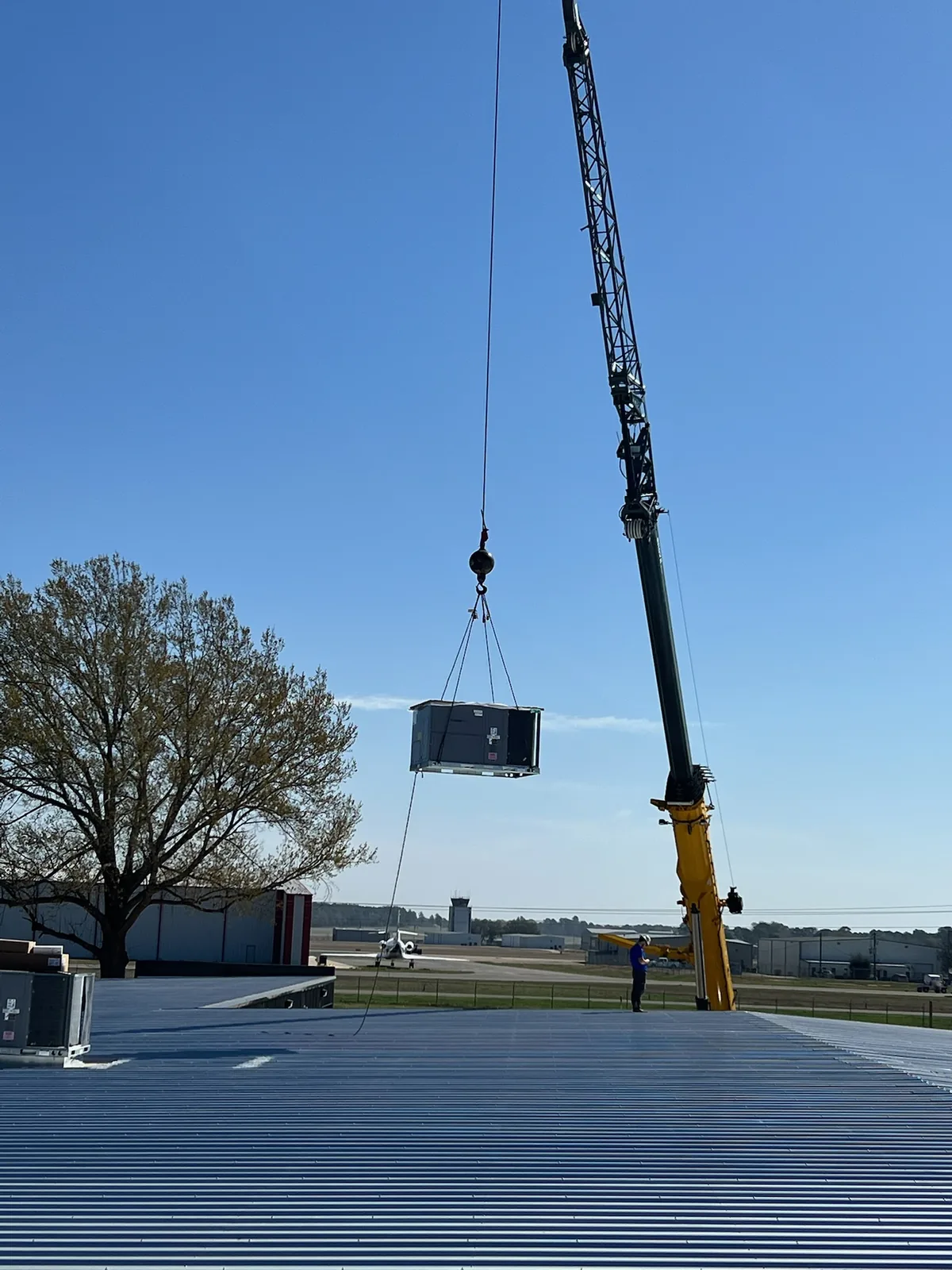 Crane lifting a packaged HVAC unit onto a commercial roof during an All Seasons installation