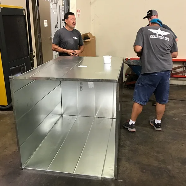 JD's A/C staff in the shop beside a fabricated sheet-metal plenum