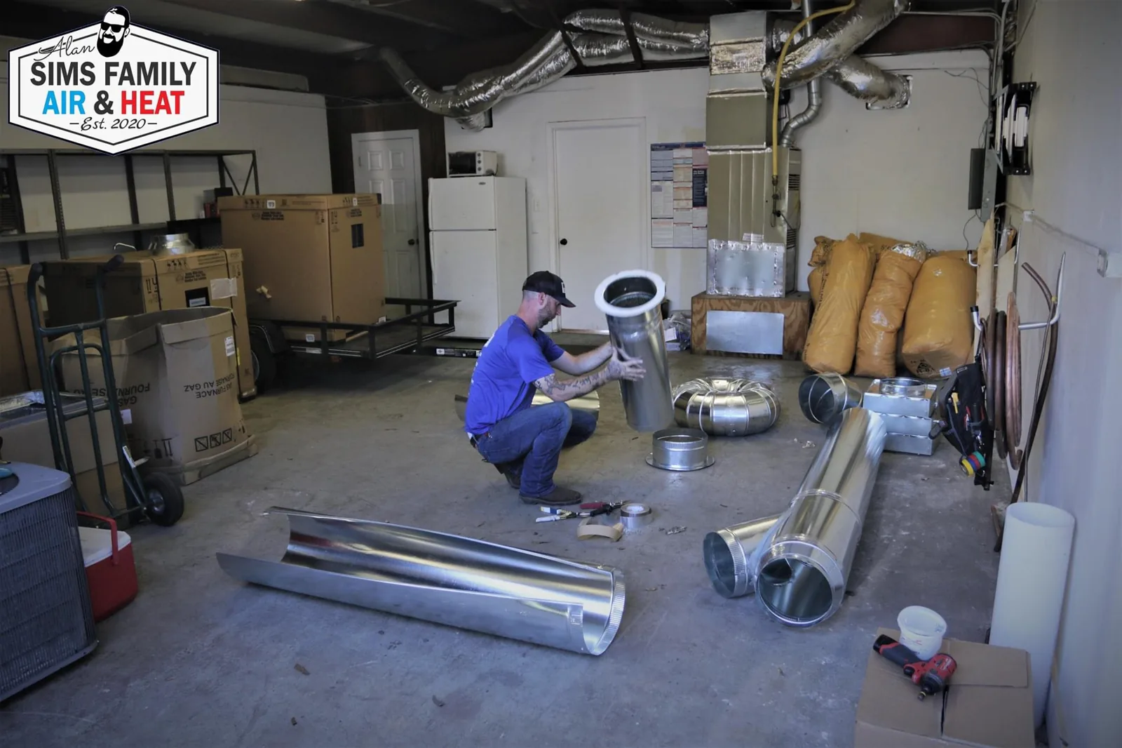 Sims Family technician working with ductwork fittings in a utility room