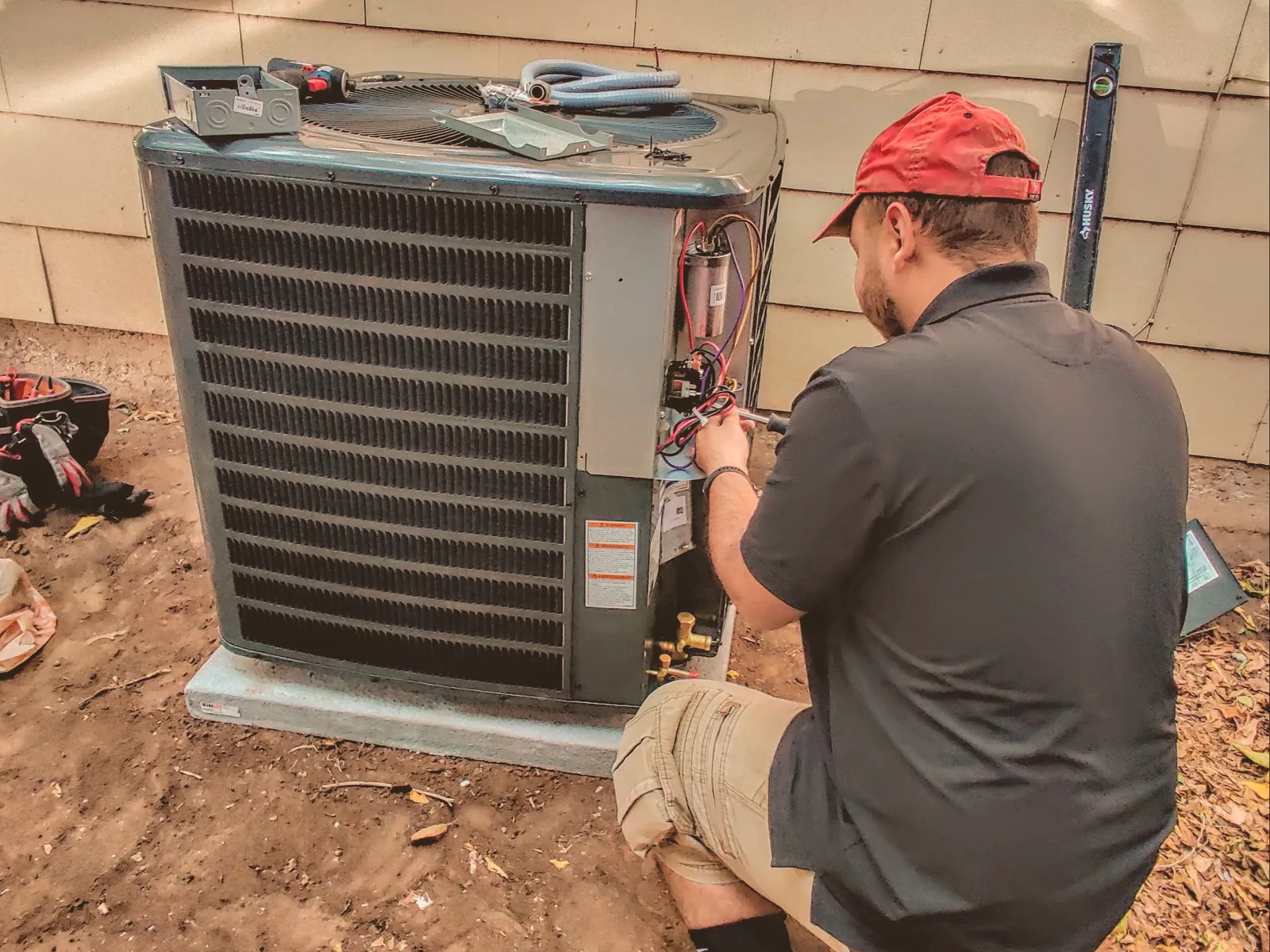 EGS Heating and Air technician servicing an outdoor AC unit