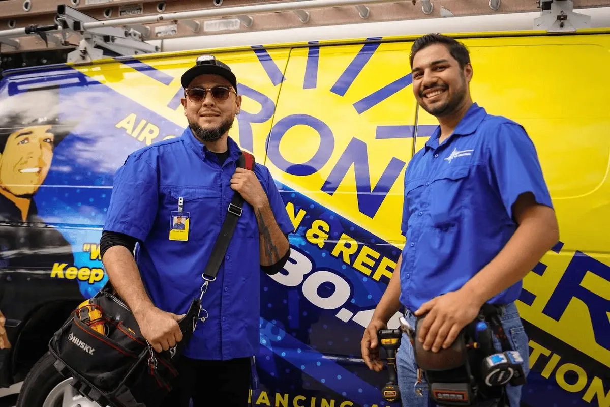 Two Frontier technicians with tool bags in front of a Frontier van