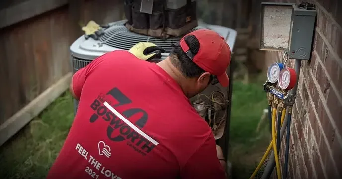 Bosworth technician checking refrigerant pressures at an outdoor AC unit