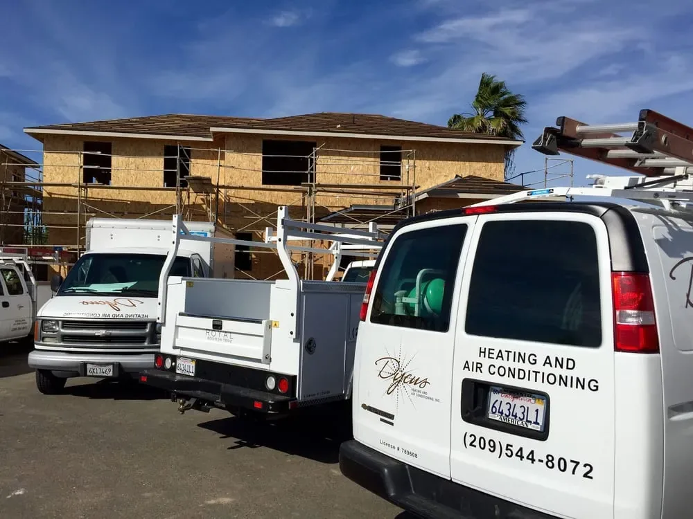 Dycus Heating and Air Conditioning service vans parked at a construction site
