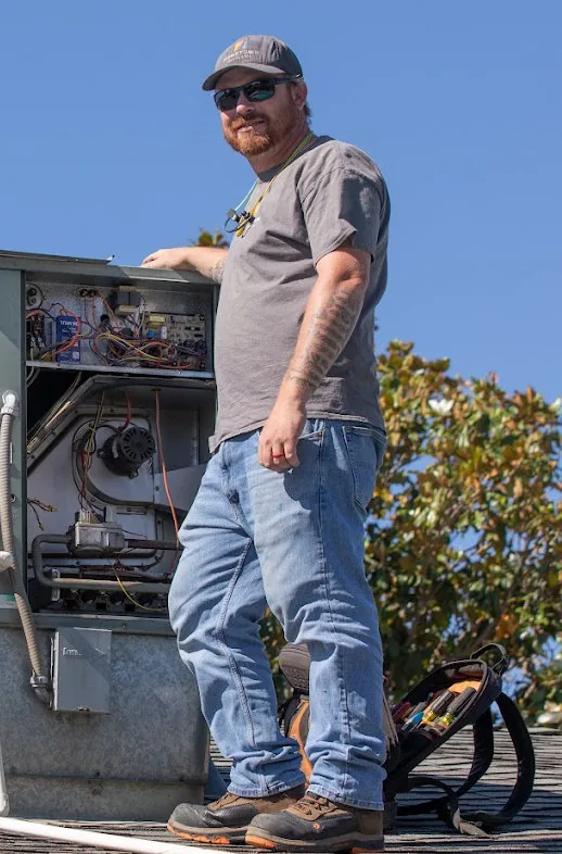 Hometown Heating & Air founder Ryan beside a rooftop HVAC unit he is servicing