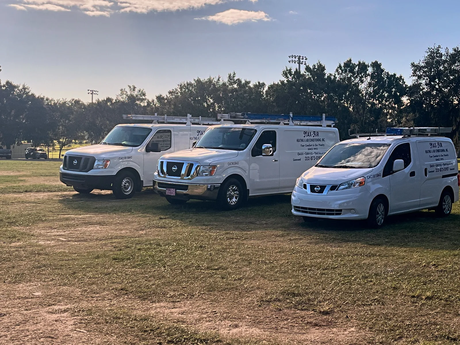 Three Max-Air service vans parked in a field