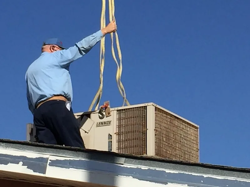 Redhawk technician guiding a Lennox rooftop unit lifted by crane