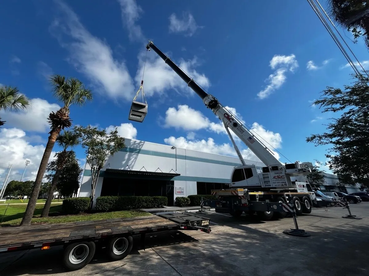Crane lifting a rooftop air conditioning unit onto a commercial building