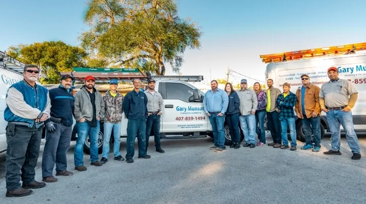 Gary Munson Heating & Air Conditioning team in front of the company service trucks