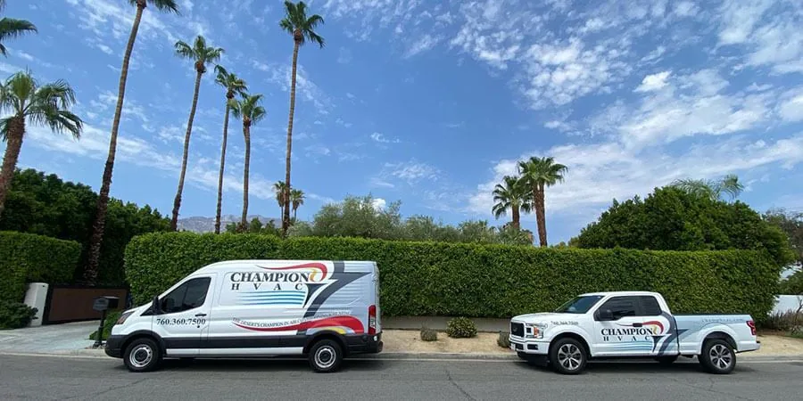 Champion HVAC van and pickup parked on a palm-lined street