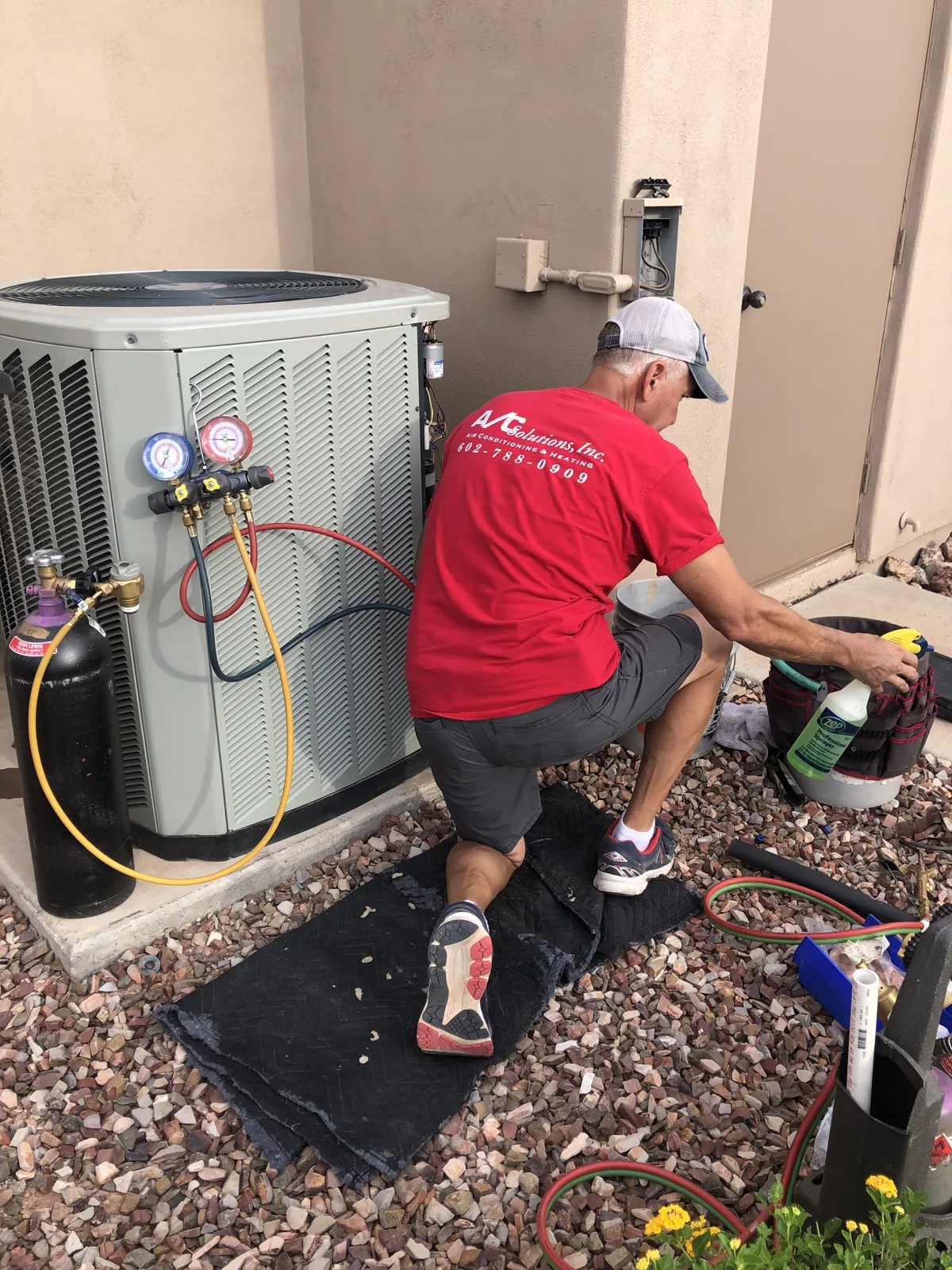 AC Solutions technician servicing an outdoor condenser