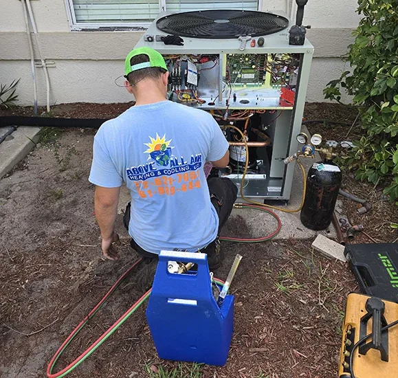 Above All Air technician in a company T-shirt servicing an outdoor unit
