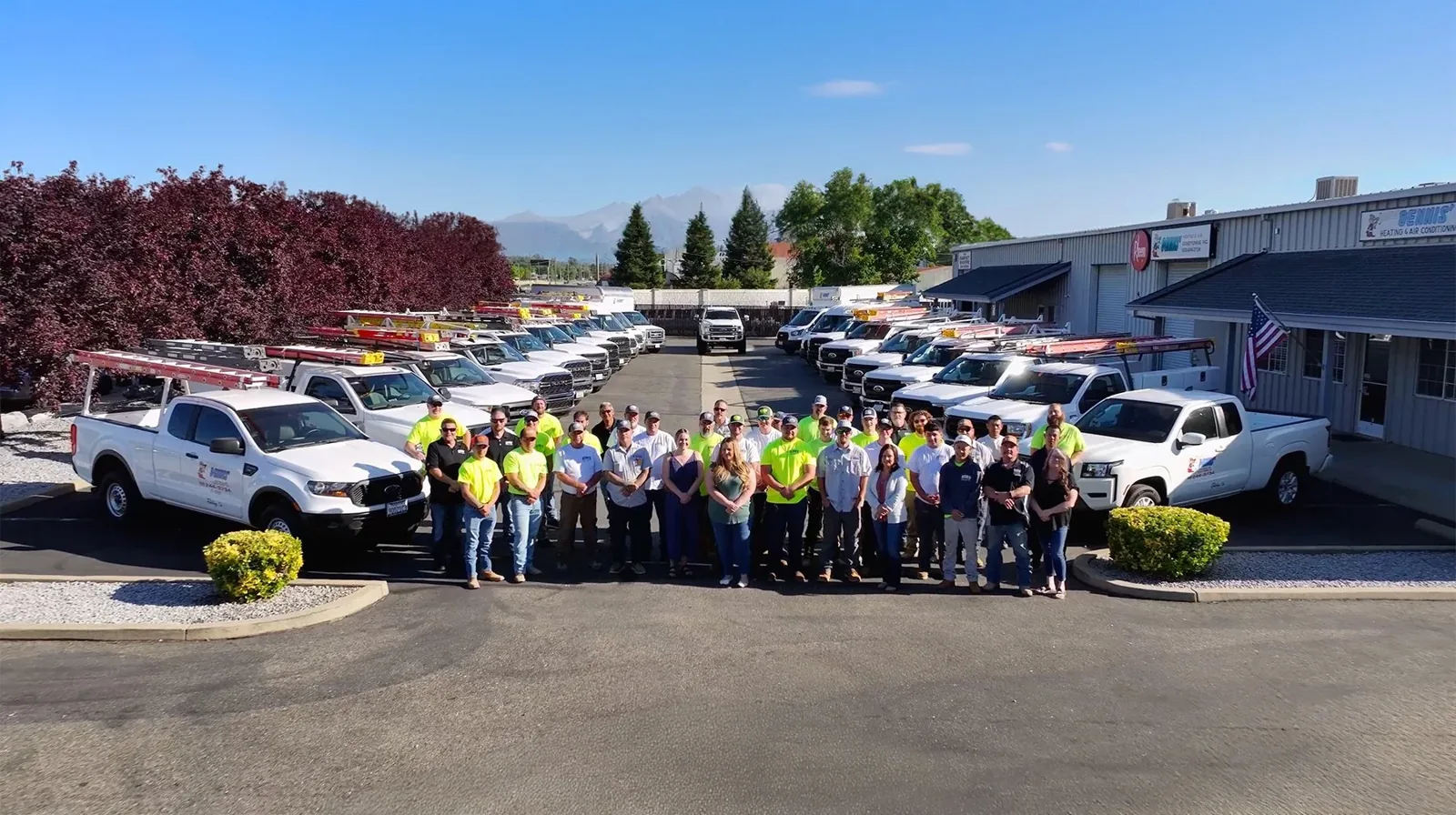 Dennis' Heating & Air Conditioning team in front of its fleet of service trucks