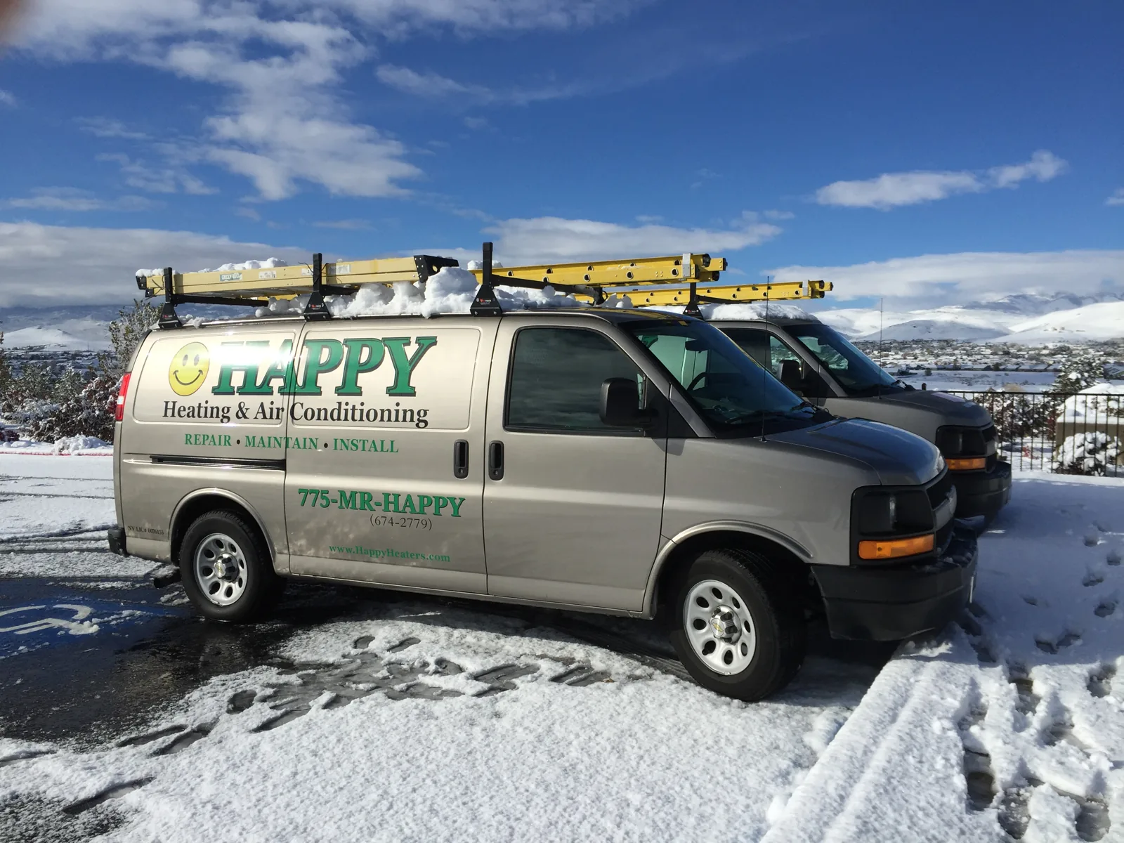 Happy Heating & Air Conditioning vans parked in the snow