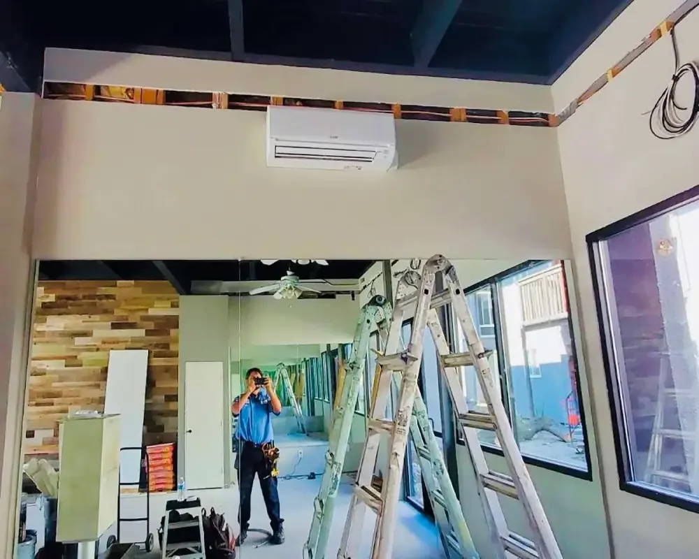 Wall-mounted mini-split installed by Prime Genius, technician reflected in a mirror