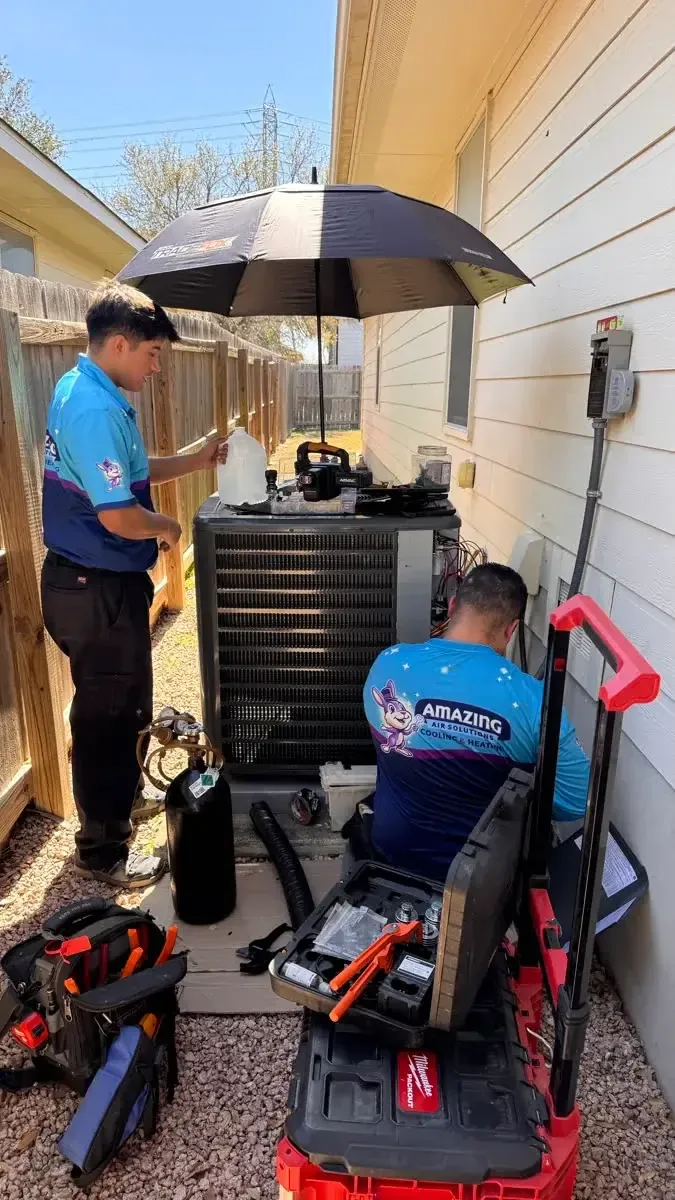 Two Amazing Air Solutions technicians working on an outdoor unit