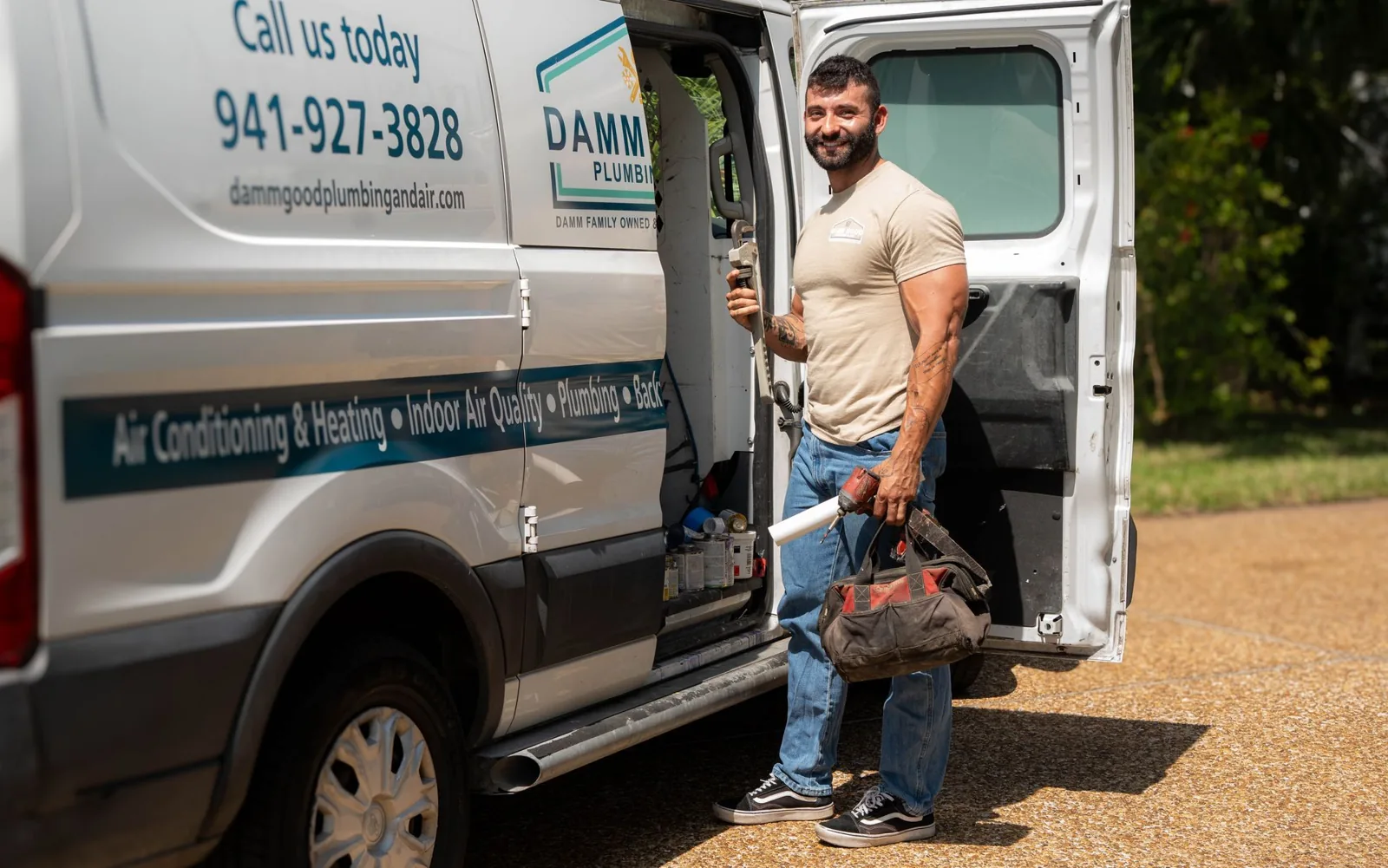 Damm Good Plumbing & Air technician beside a branded service van