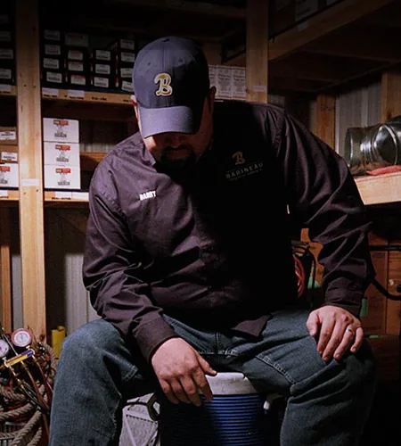 Barineau team member in a company cap and jacket in the parts room