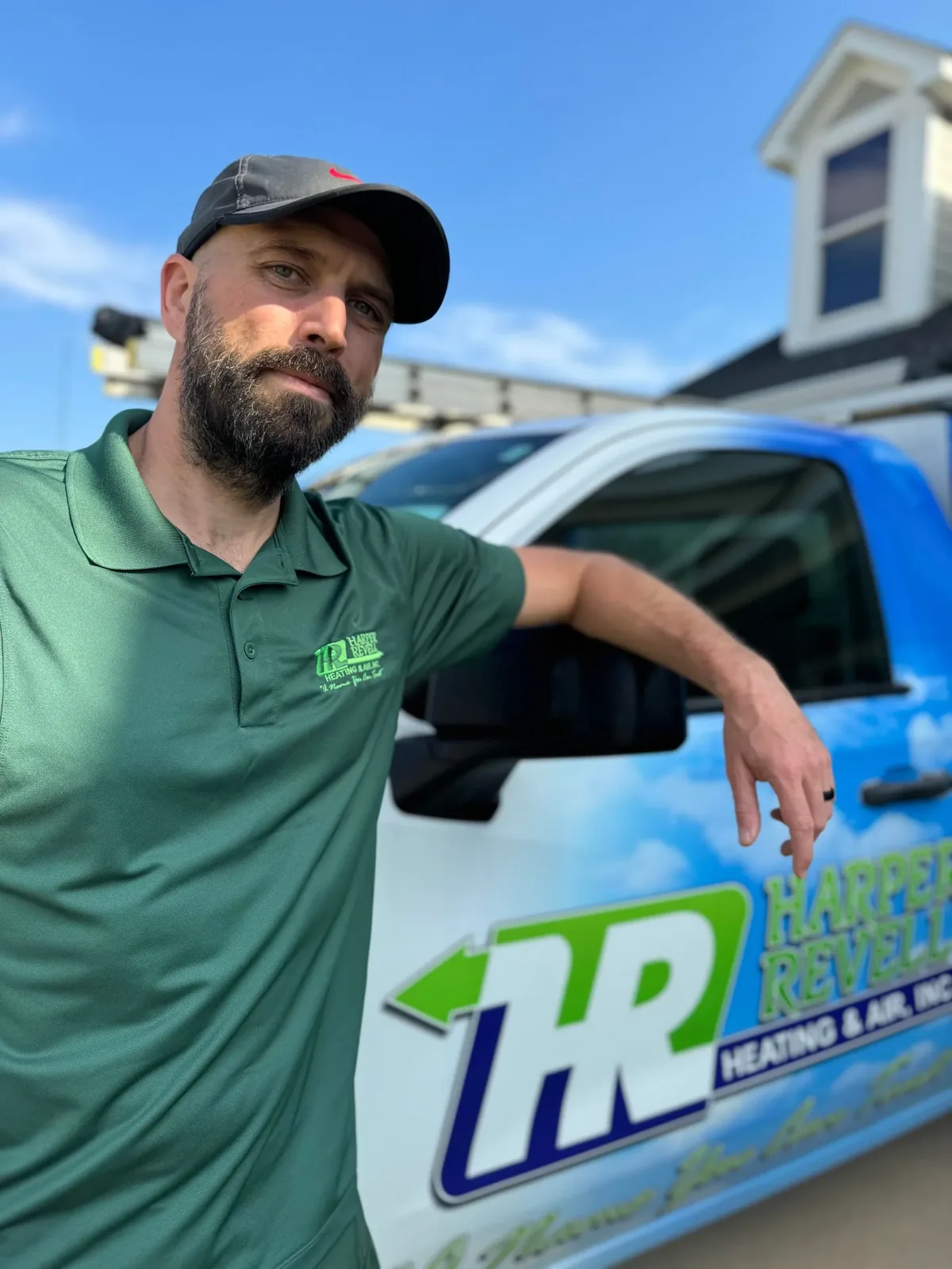Harper Revell technician leaning on a branded company truck