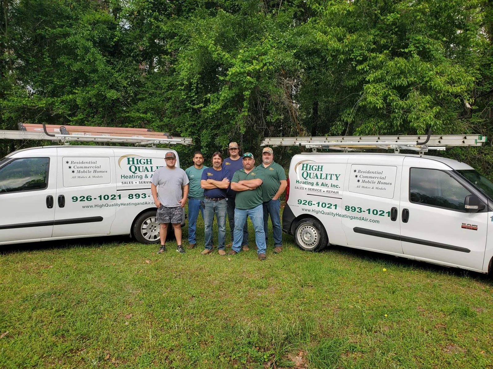 High Quality Heating and Air team standing between two company vans