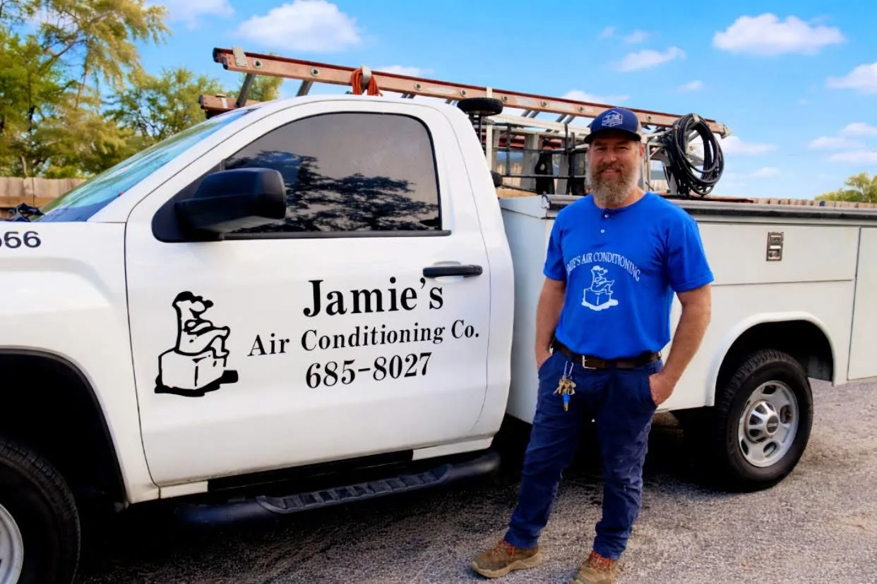 Jamie's Air Conditioning technician beside a company service truck
