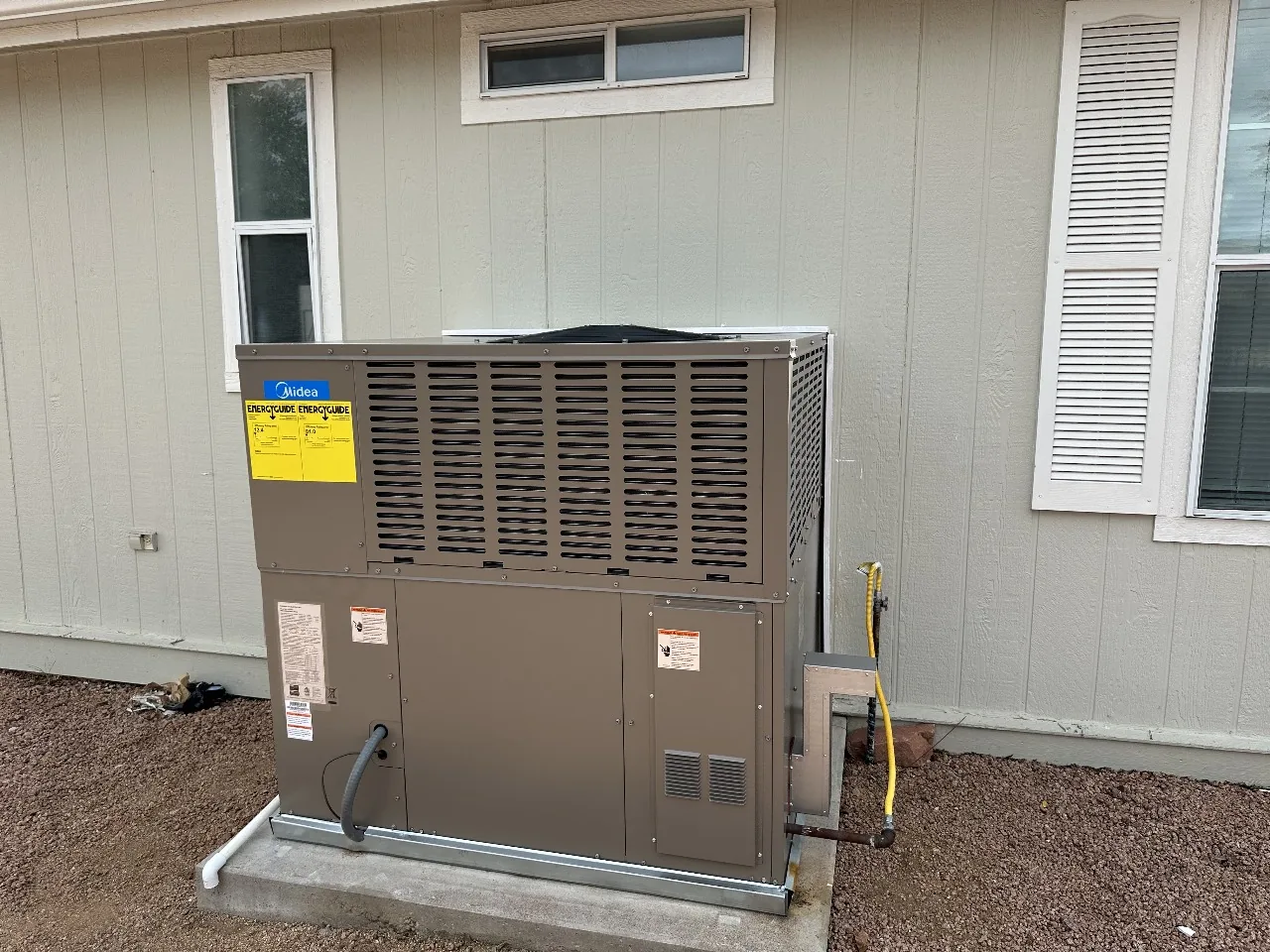 Newly installed packaged heating and cooling unit beside a house