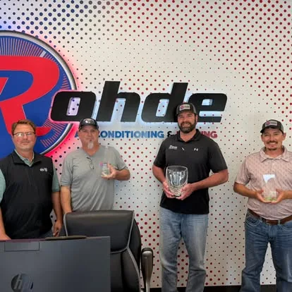 Rohde team members holding awards in front of the company sign