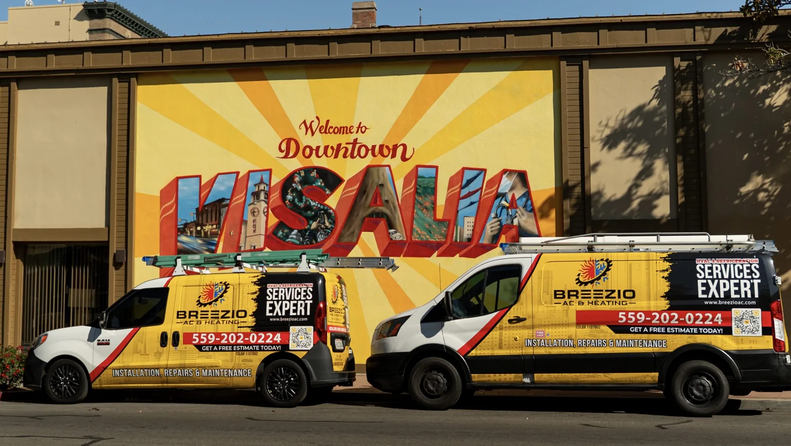 Two Breezio AC & Heating vans in front of the Downtown Visalia mural